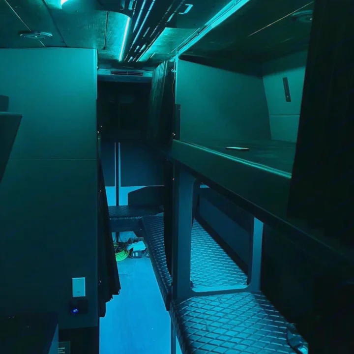 Step inside this RV rental! The interior features stacked bunk beds under atmospheric blue lighting, perfect for mobile adventures.. Mercedes Sprinter Freight Liner 2020