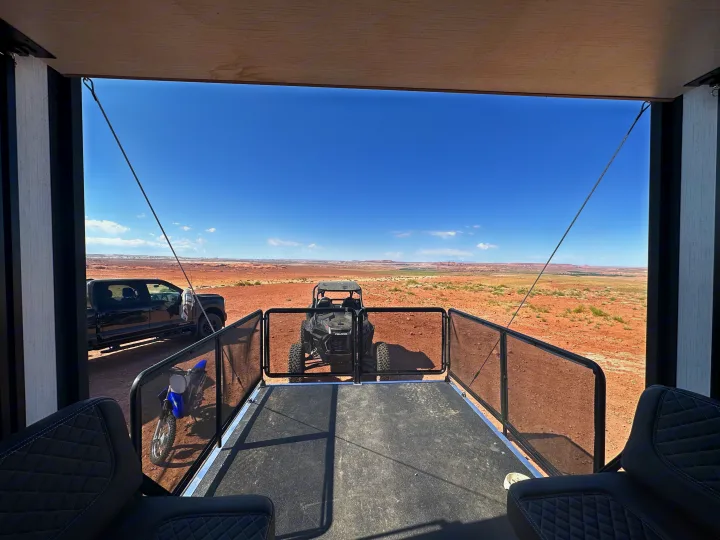 RV rental patio overlooking a vast desert landscape with off-road vehicles: a truck, Polaris RZR, and dirt bike.. Heartland Lithium 2515S 2022
