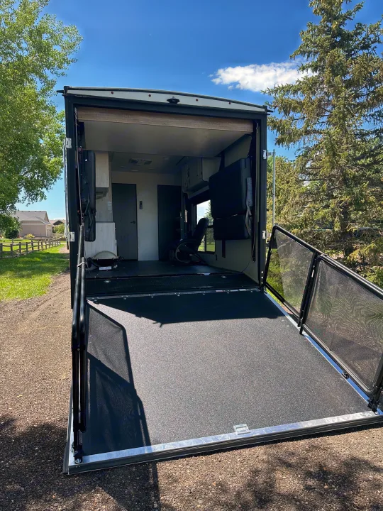 Sunny RV rental with ramp lowered to create a spacious patio deck, featuring mesh railings & an inviting interior view.. Heartland Lithium 2515S 2022