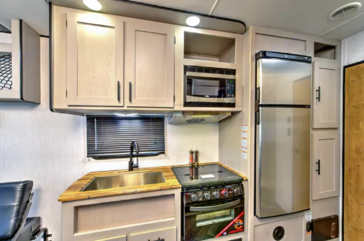 RV rental kitchen featuring modern appliances: sink, stove, microwave, & fridge. Perfect for road trips!. Heartland Lithium 2515S 2022
