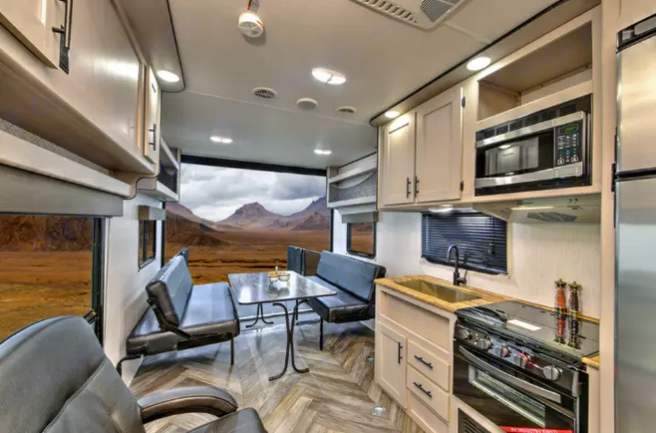 Spacious RV rental interior with kitchen, dining area, and a large rear opening revealing a desert mountain view.. Heartland Lithium 2515S 2022