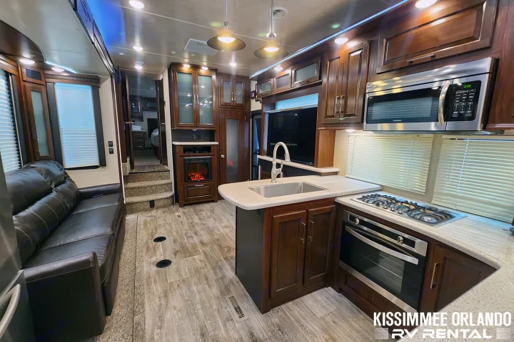 Spacious RV rental interior with a modern kitchen, comfortable living area, and cozy electric fireplace.. Heartland Cyclone 2019
