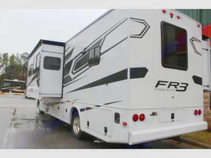 A white Forest River FR3 motorhome with an extended side slide-out, parked on a wet lot, ready for your RV rental trip.. Forest River FR3 30DS 2023