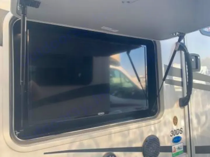 An open compartment on an RV rental reveals a flat-screen TV, perfect for outdoor entertainment during your trip.. Forest River FR3 30DS 2023