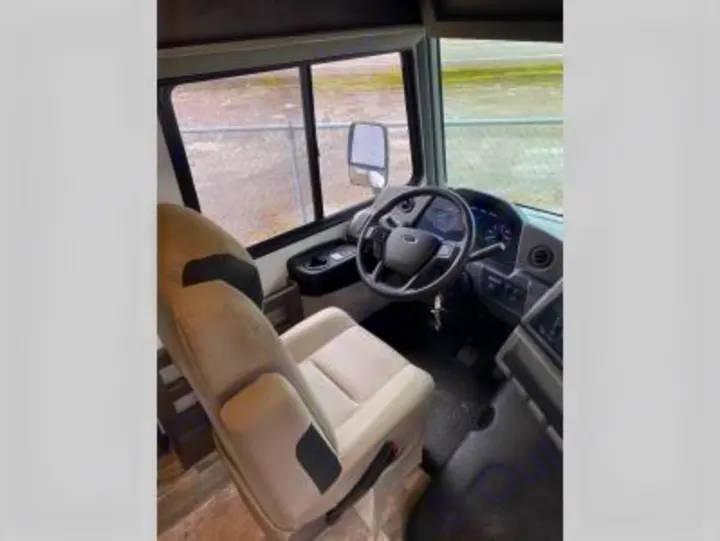 View of the rv rental cockpit, showing the beige driver's seat, steering wheel, and dashboard area, ready for travel.. Forest River FR3 30DS 2023