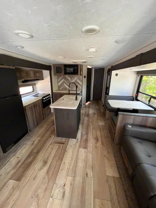 Spacious RV rental showcasing a modern kitchen with an island, black appliances, a dinette, and wood-look flooring.. KZ Sportsmen LE 303KBLE 2021