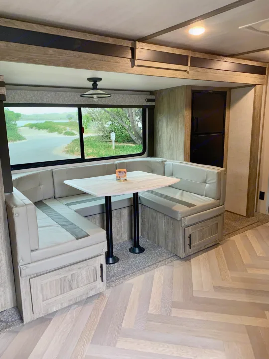 This RV rental's modern interior showcases a light gray dinette, dining table, and a scenic window view overlooking the water.. Forest River Salem Hemisphere HL 2021