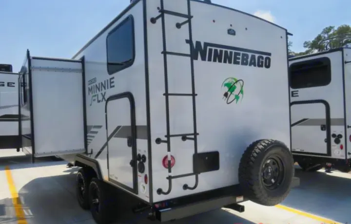 Winnebago Micro Minnie FLX travel trailer, a compact RV rental with a rear ladder, spare tire, and expandable side. Ready for adventure.. Winnebago Micro Minnie FLX 2100BH 2022