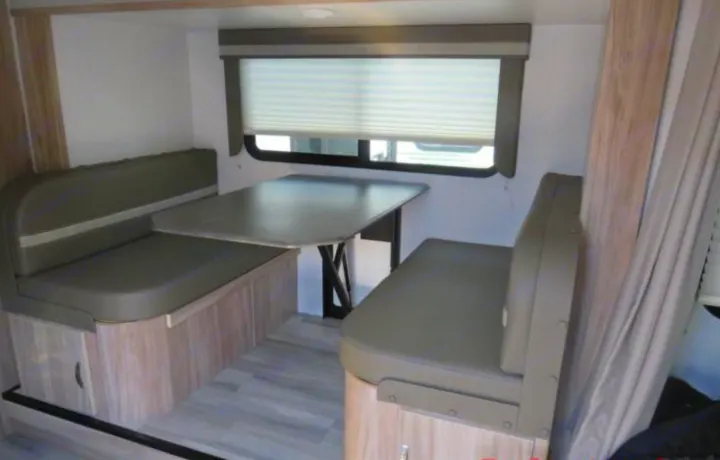 RV rental dinette with comfortable booth seating, a table, and a window with blinds, ideal for meals or relaxation.. Winnebago Micro Minnie FLX 2100BH 2022
