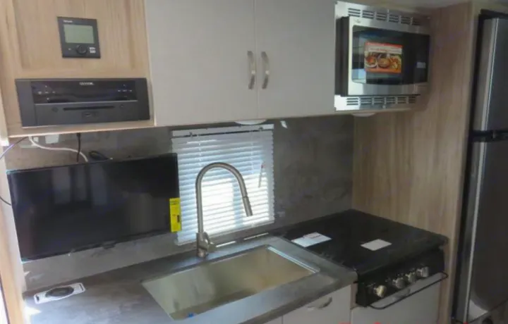 RV rental kitchen: Features a sink, stovetop, microwave, fridge, and TV for comfortable travel.. Winnebago Micro Minnie FLX 2100BH 2022