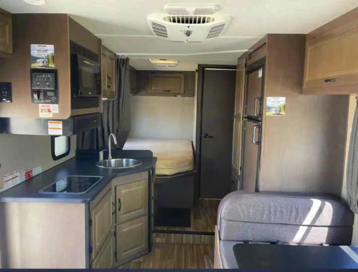 Spacious RV rental interior showing kitchen, dinette, fridge, and sleeping area, perfect for road trips.. Thor Majestic 2018