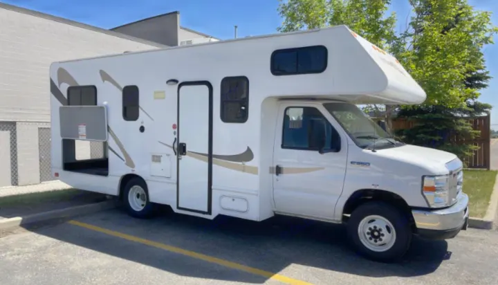 White Class C RV, perfect for rv rental adventures, parked outdoors with rear storage open for equipment.. Thor Majestic 2018
