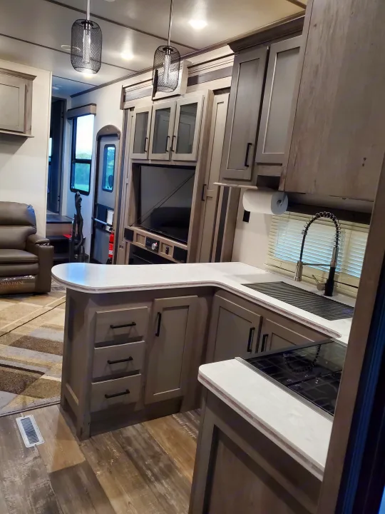 Explore this inviting rv rental interior: a sleek kitchen, comfortable living space, and practical design.. Keystone Raptor 2020