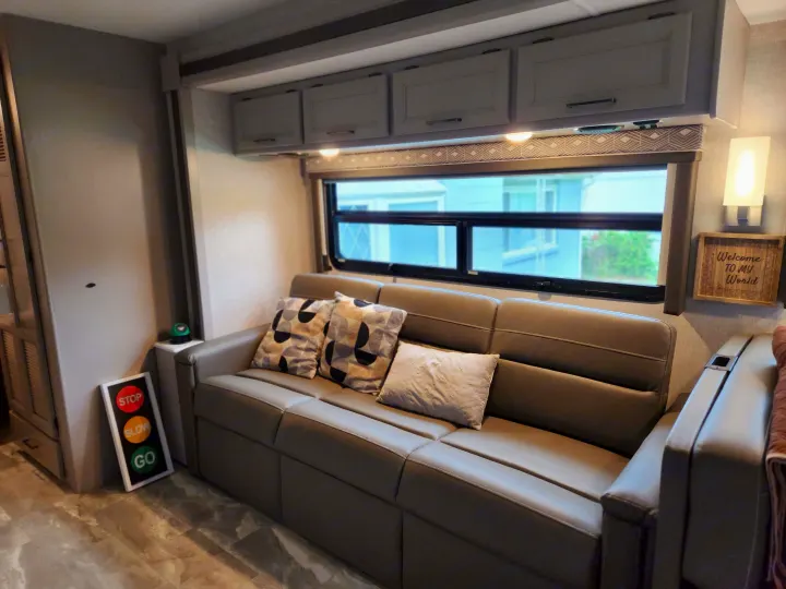 This inviting rv rental offers a comfortable sofa, window, cabinets, and a 'Welcome to My World' sign.. Thor Windsport 2023