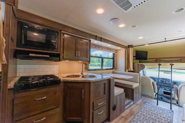 Modern rv rental interior with a full kitchen (microwave, stove, sink) and comfortable dinette, ideal for travel.. Jayco Redhawk 2019