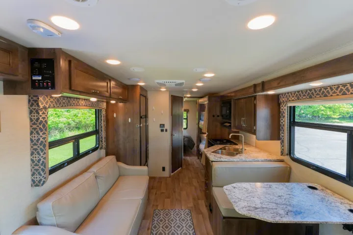 Explore this modern RV rental interior featuring a bright living room, equipped kitchen, and dining area, leading to a rear bedroom.. Jayco Redhawk 2019