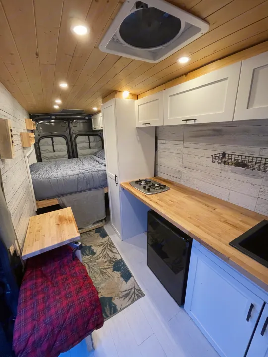Cozy RV rental interior with a comfortable bed, well-equipped kitchen, and smart storage for your next adventure.. Ford Transit Custom 2019