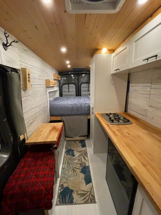 Cozy RV rental interior with full kitchen, comfy bed, and seating area in a well-designed camper van.. Ford Transit Custom 2019