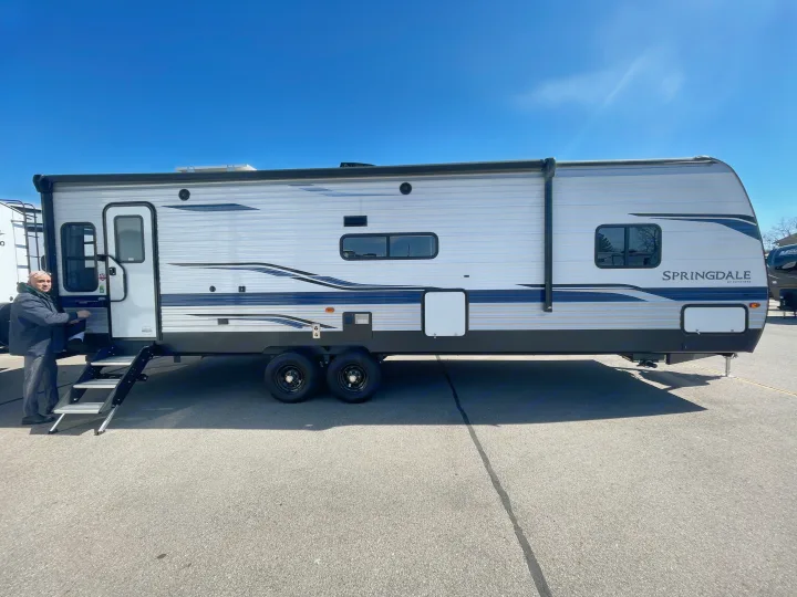 This Springdale by Keystone travel trailer, a great RV rental, is seen with a man on its entry steps.. Keystone RV Springdale 2023