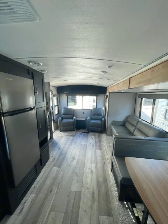 Bright rv rental interior. Modern living area with recliners, dinette, and fridge. Perfect for road trips.. Keystone RV Springdale 2023