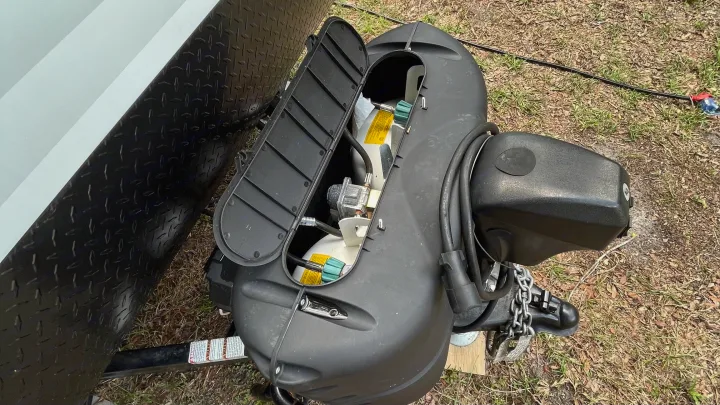 View of an RV rental's front hitch area. Open cover displays propane tanks, crucial for power and heating while camping.. Riverside RV Retro 2022