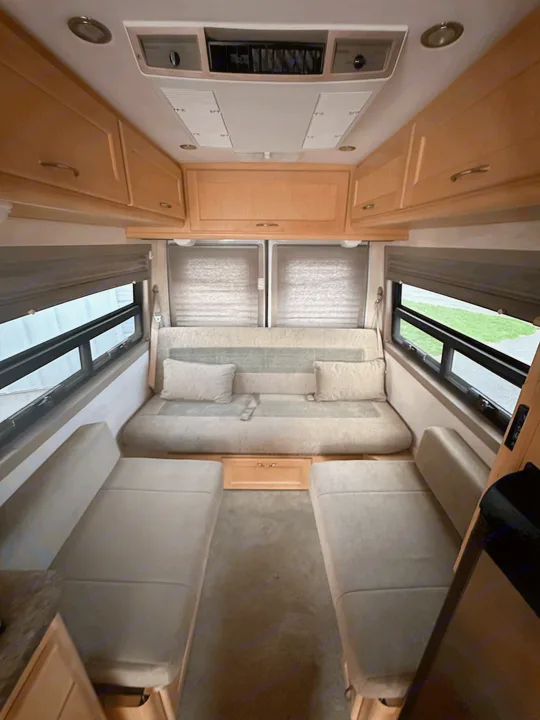 RV rental's inviting interior: featuring a versatile sofa bed, two separate seats, wood cabinets, and large windows.. Pleasure-Way Pleasure-Way Class B 2005