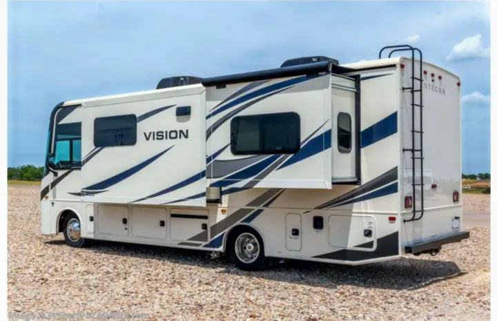 Large white recreational vehicle (RV) with a slide-out deployed, parked on gravel, ready for rv rental.. Entegra Coach Vision 2021