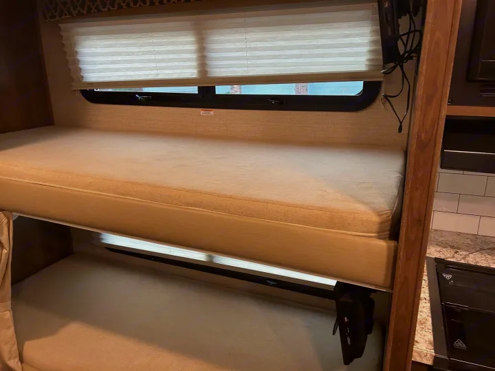 RV rental: Bright interior featuring comfy stacked bunk beds with mattresses, a window, and a kitchen glimpse.. Jayco Redhawk 2020
