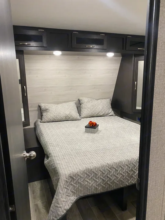 Cozy RV rental bedroom with gray bedding, overhead storage, and LED lights, ideal for comfortable travel accommodation.. Jayco Jay Flight 2021