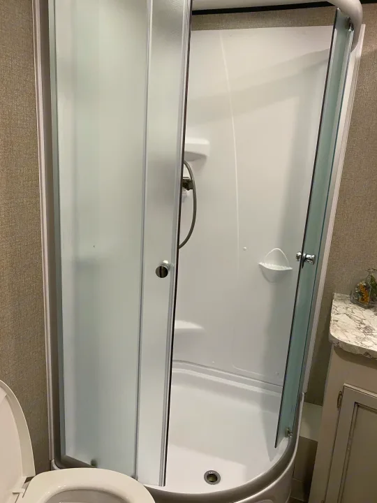 Compact RV rental bathroom: corner shower with frosted glass doors, next to a toilet and vanity.. Jayco Jay Flight 2021