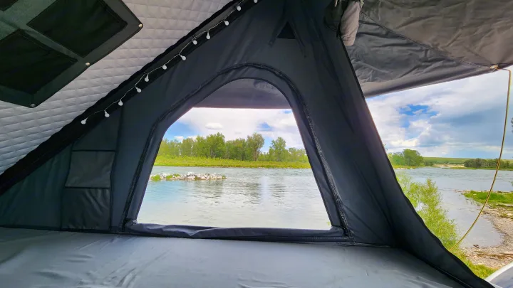 Serene river view from an RV rental rooftop tent. Cozy interior with quilted ceiling and string lights offers a peaceful nature escape.. Toyota Highlander 2005