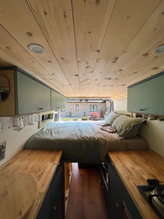 Cozy RV rental interior: wood-paneled ceiling, bed, compact kitchen, and storage for your next adventure.. Other Sprinter Van 2017