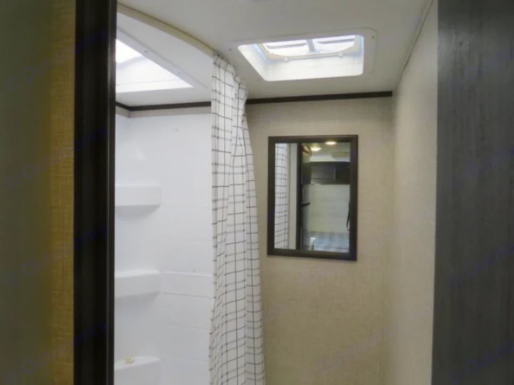 An RV rental bathroom features a white shower, a checkered curtain, two skylights, and a mirror reflecting the interior.. Jayco Jay Flight SLX STX Edition 2023