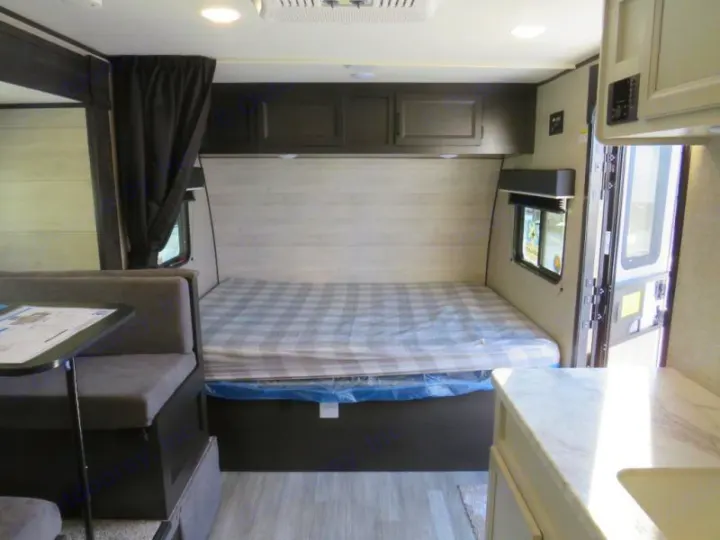 RV rental interior featuring a comfortable bed and dining area, with ample overhead storage.. Jayco Jay Flight SLX STX Edition 2023