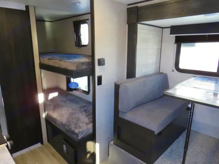 This RV rental interior features practical bunk beds and a comfortable dinette with bench seating and a table.. Jayco Jay Flight SLX STX Edition 2023