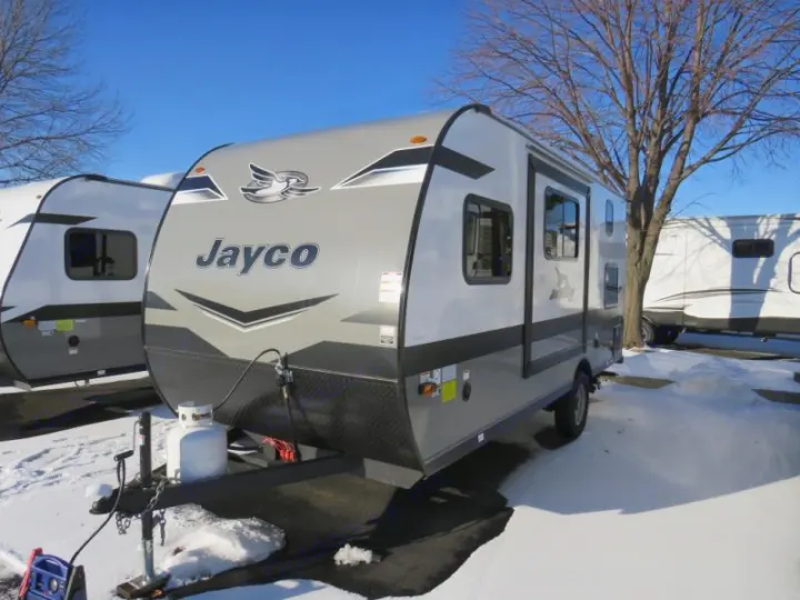 Jayco travel trailer RV rental, a grey & white camper parked in snow on a sunny day with bare trees.. Jayco Jay Flight SLX STX Edition 2023