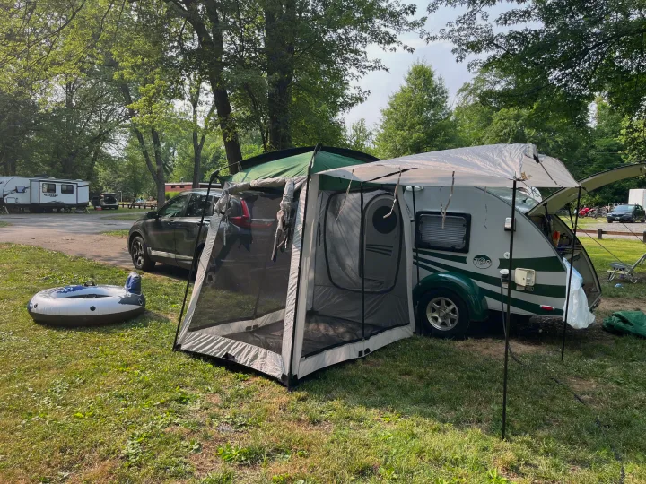Teardrop camper with screen room, car, and inflatable tube at a sunny RV rental campsite, perfect for outdoor recreation.. T@G T@G Trailer 2015