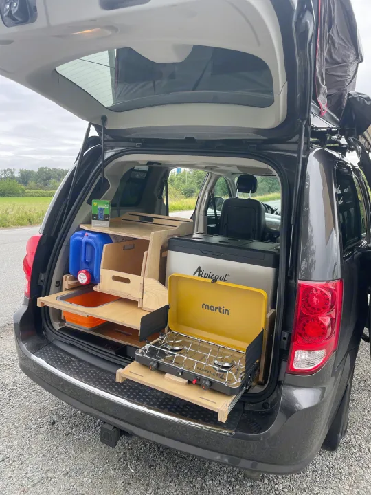 Explore with this RV rental! A minivan campervan shows a custom kitchenette: slide-out stove, fridge, water, and storage.. Dodge Caravan 2015