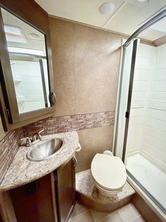 This clean RV rental bathroom features a compact vanity with sink, toilet, and shower. Ideal for road trips.. Thor Chateau 2020