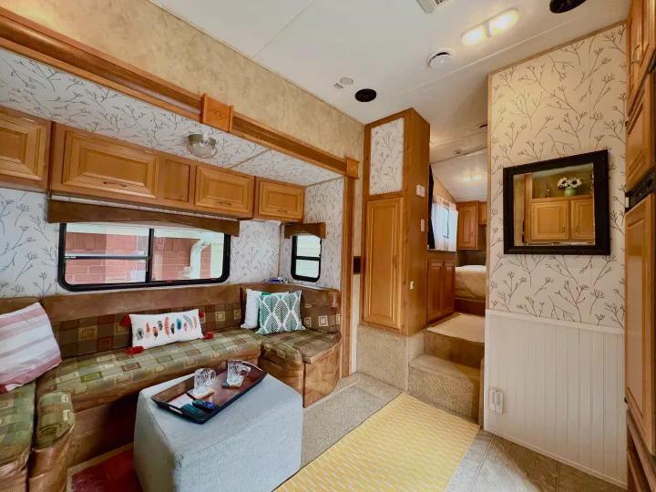 An RV rental's inviting living area with patterned walls, comfy seating, wood cabinets, and a glimpse of the bedroom.. Keystone RV Raptor Toy Hauler 2007