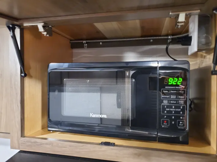 A Kenmore microwave is mounted securely in a wooden cabinet, common in an rv rental kitchen setup, displaying 8:22 AM.. Imperial Outdoors XploreRV 2023
