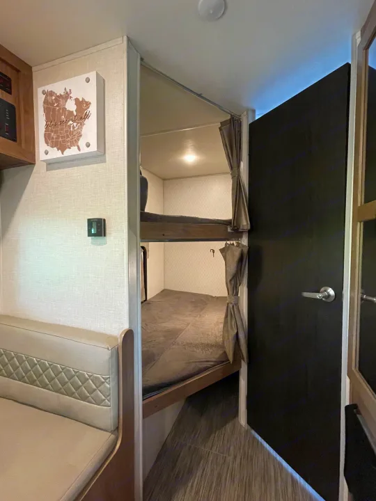 RV rental interior showing cozy bunk beds, a dinette, and wall controls. Ideal for family road trips.. Forest River No Boundary 2020