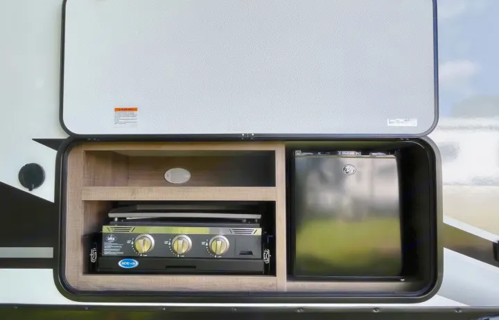 This RV rental features a convenient outdoor kitchen setup: a pull-out grill, mini-fridge, and storage. Ideal for travel.. Grand Design Other 2023