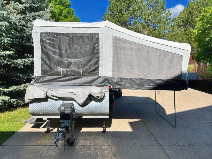 A modern pop-up camper RV rental ready for adventure, parked on a sunlit driveway amidst lush trees.. Quicksilver Quicksilver Livin Lite 2011