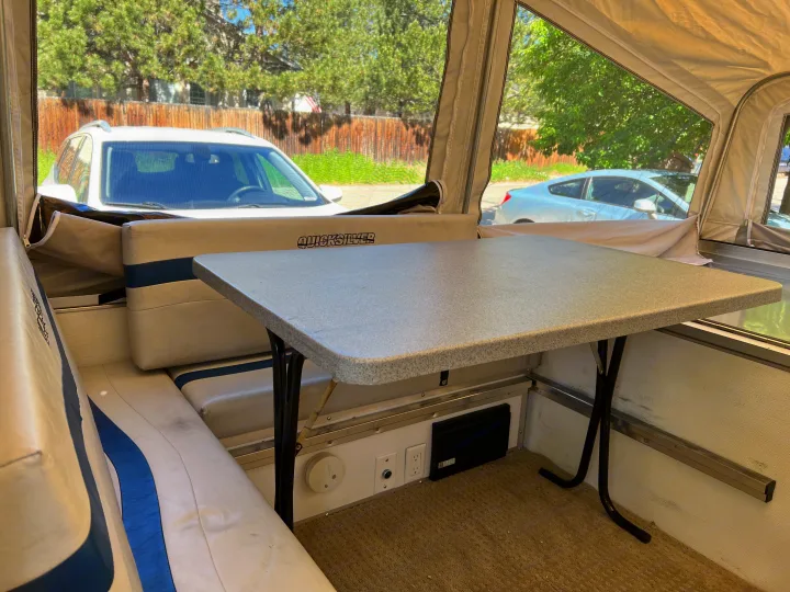 Inside a Quicksilver RV rental: cozy dinette area with table, seats, and view of parked cars.. Quicksilver Quicksilver Livin Lite 2011