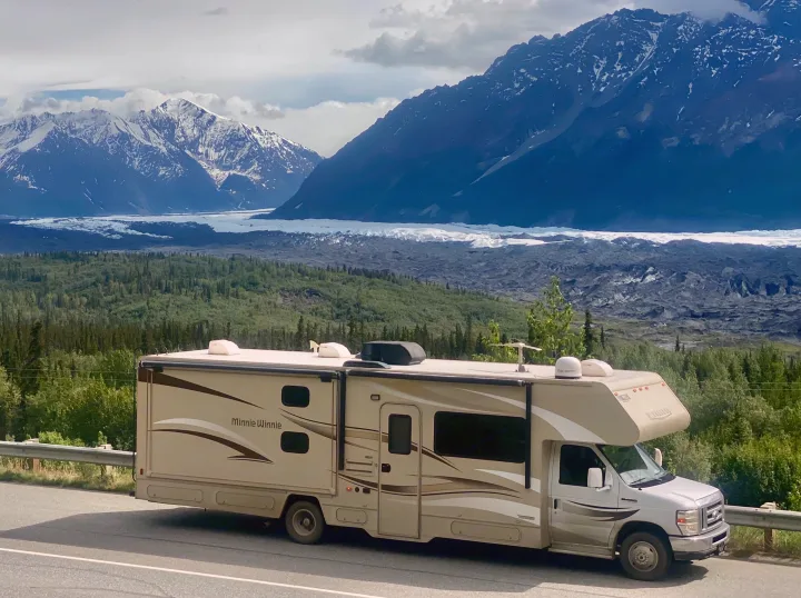 Minnie Winnie RV rental parked by a road, revealing snow-capped mountains, a sprawling glacier, and lush forest views.. Winnebago Minnie Winnie 2015