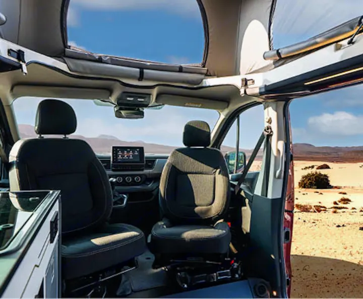 Interior of an RV rental pop-top camper van with front seats & dash, open to a desert landscape. Perfect for road trips!. HANROAD TREK 4 2023