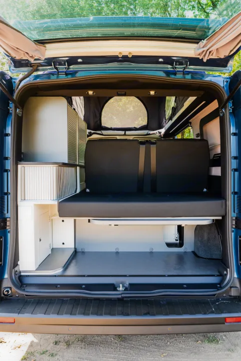 Rear view of a modern camper van interior with modular storage, convertible seating, and a pop-top.. HANROAD TREK 4 2023