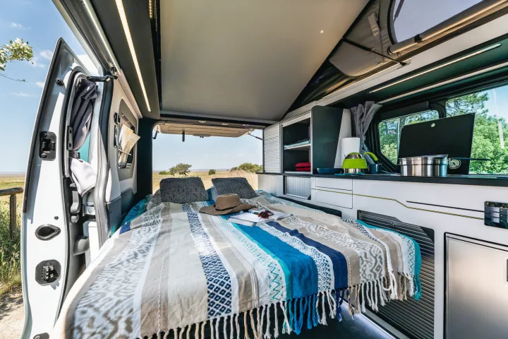 Comfortable campervan interior with bed, kitchen, and nature views. Perfect for an RV rental adventure.. HANROAD TREK 4 2023