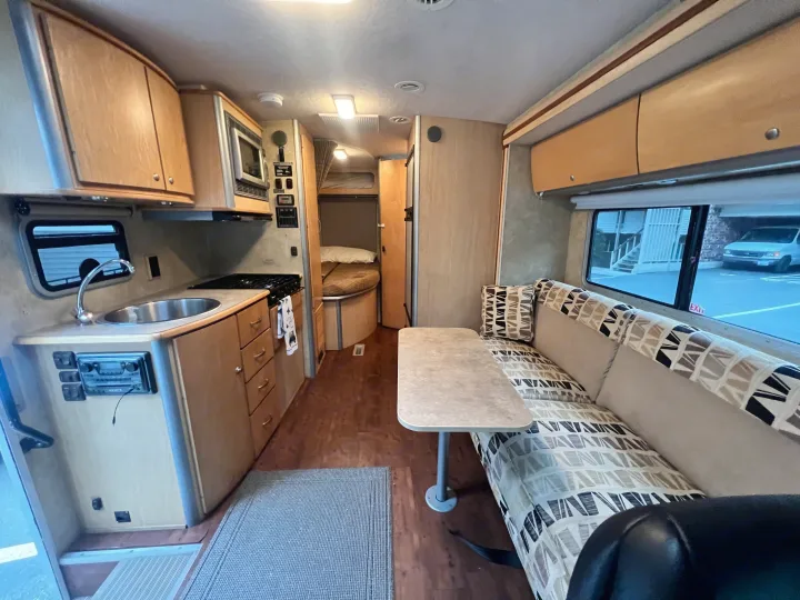 Spacious RV rental interior with full kitchen, comfortable dinette, and a cozy sleeping area in the back.. Winnebago View 2008